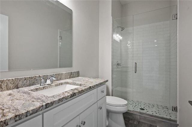 bathroom featuring vanity, toilet, and a shower with shower door