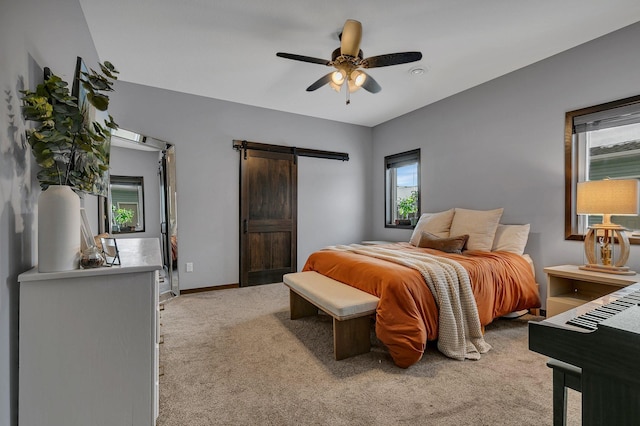 carpeted bedroom with a barn door and ceiling fan