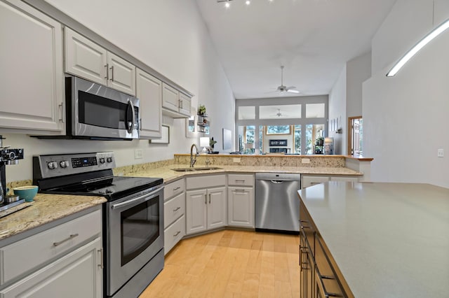 kitchen with sink, ceiling fan, appliances with stainless steel finishes, light hardwood / wood-style floors, and kitchen peninsula