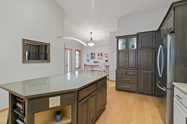 kitchen featuring stainless steel fridge, hanging light fixtures, dark brown cabinets, and light hardwood / wood-style flooring