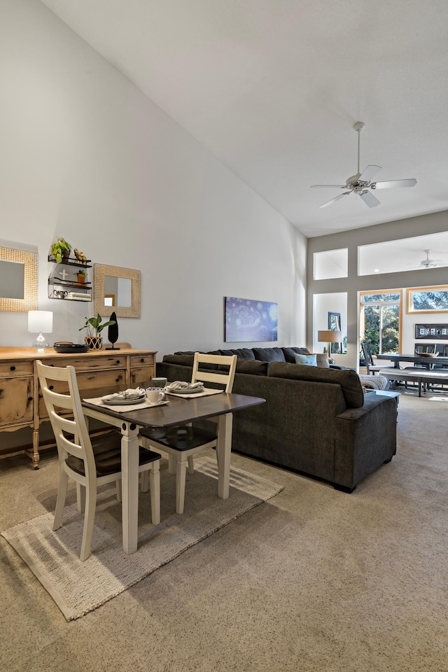 carpeted dining area featuring high vaulted ceiling and ceiling fan