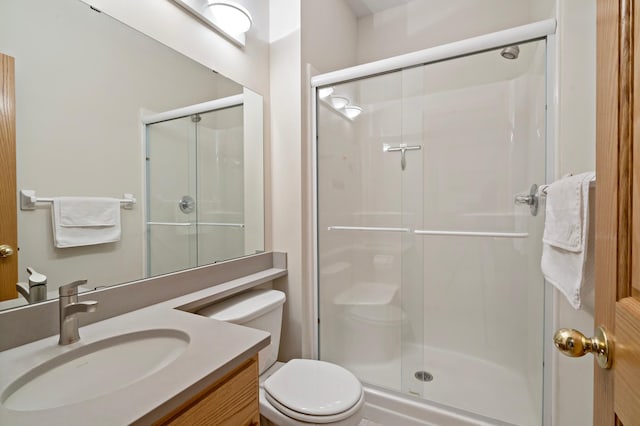 bathroom with a shower with door, vanity, and toilet