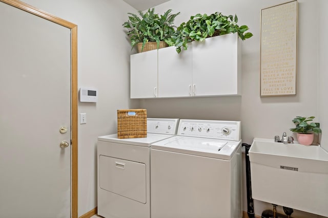 clothes washing area with cabinets, washer and clothes dryer, and sink