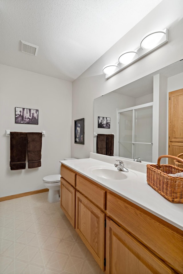 bathroom with vanity, a shower with door, toilet, and a textured ceiling