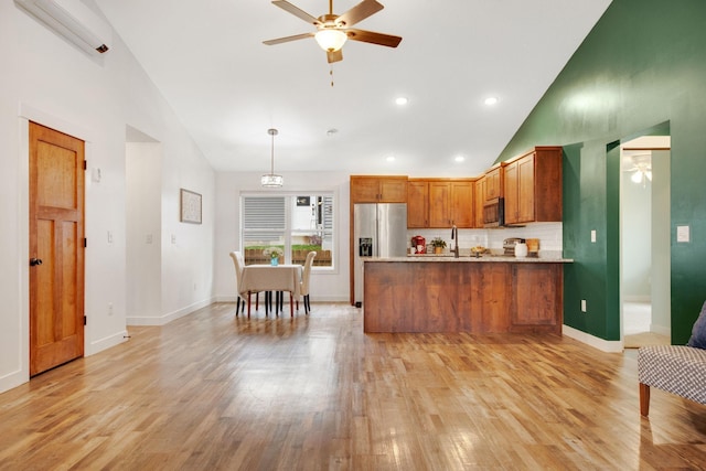 kitchen with hanging light fixtures, appliances with stainless steel finishes, kitchen peninsula, ceiling fan, and light hardwood / wood-style floors