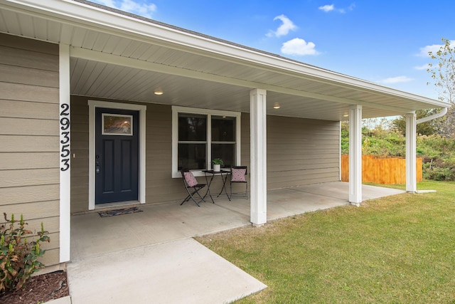 view of exterior entry with a yard and a porch