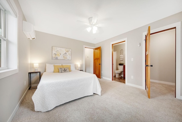 bedroom with multiple windows, light carpet, a wall mounted air conditioner, and connected bathroom