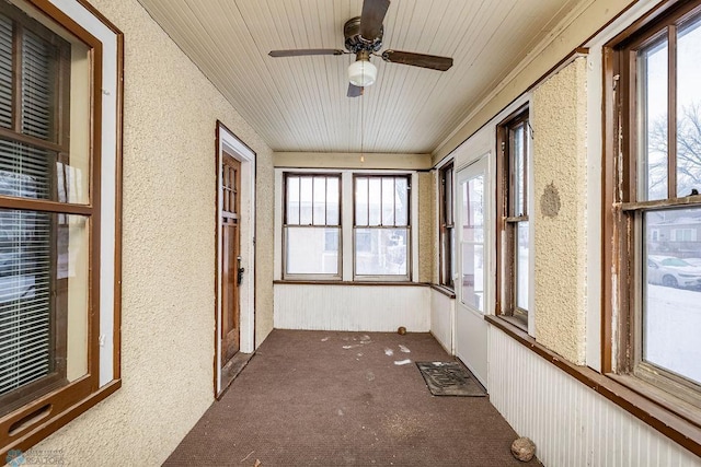 unfurnished sunroom featuring ceiling fan and plenty of natural light