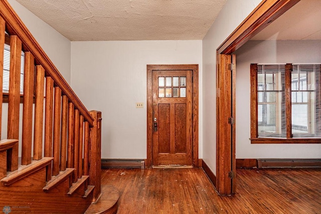 foyer with a baseboard radiator, a healthy amount of sunlight, a textured ceiling, and dark hardwood / wood-style floors