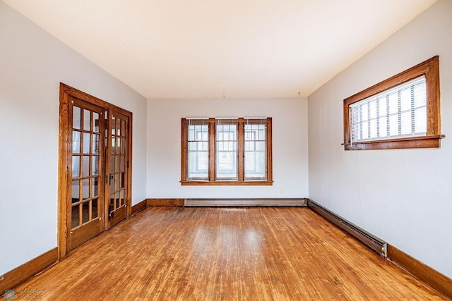 unfurnished room featuring light hardwood / wood-style flooring and a baseboard heating unit