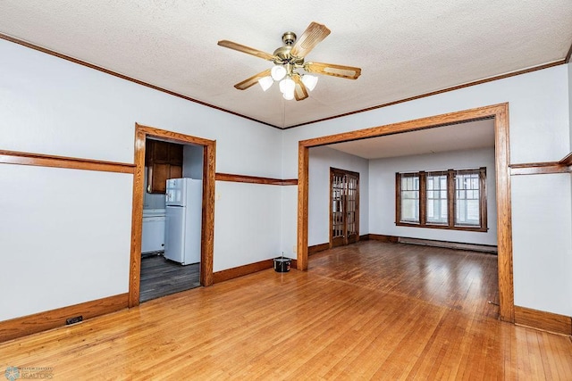 unfurnished room with a baseboard heating unit, wood-type flooring, ornamental molding, and a textured ceiling