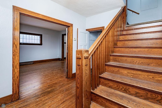 staircase with hardwood / wood-style flooring and a textured ceiling