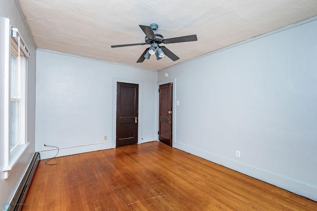 unfurnished room with hardwood / wood-style flooring, ornamental molding, ceiling fan, and baseboard heating