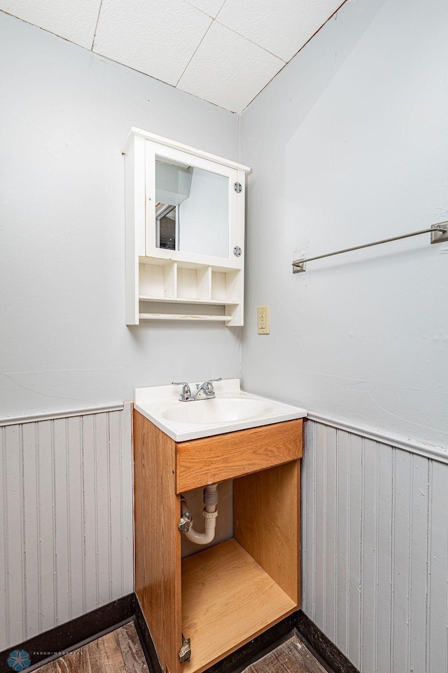 bathroom with sink, hardwood / wood-style floors, radiator, and wooden walls