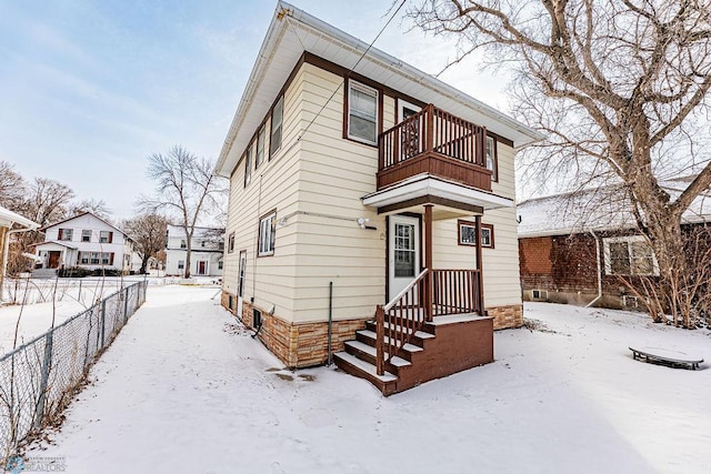 snow covered house featuring a balcony