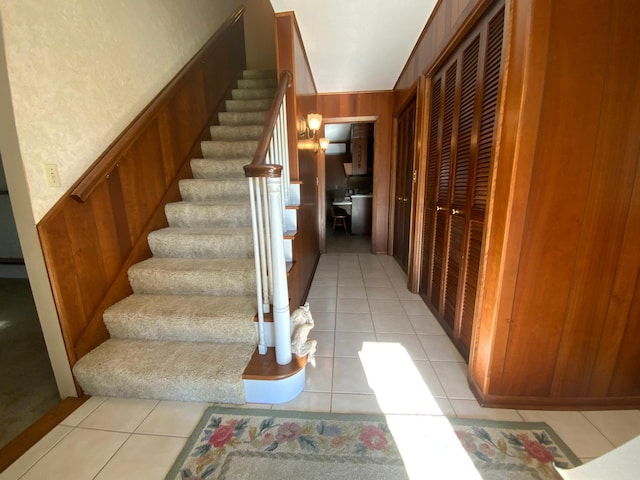 stairs featuring tile patterned flooring and wooden walls