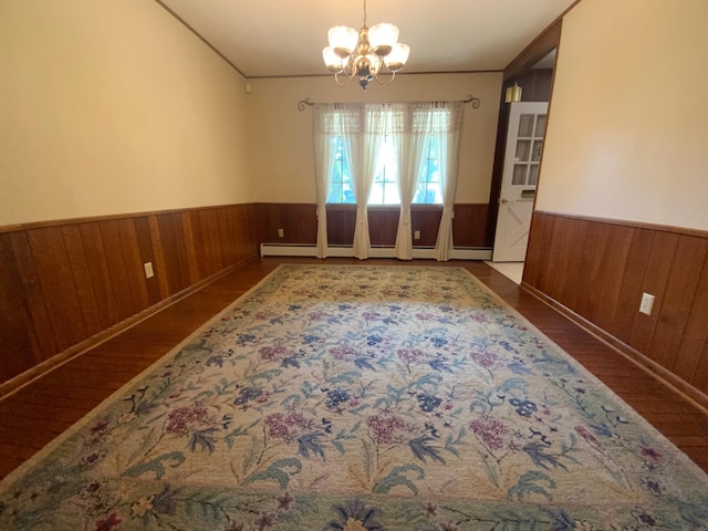 empty room featuring wooden walls, hardwood / wood-style floors, and a notable chandelier