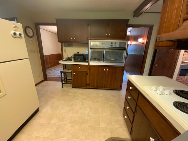 kitchen with a kitchen breakfast bar, white appliances, and beamed ceiling