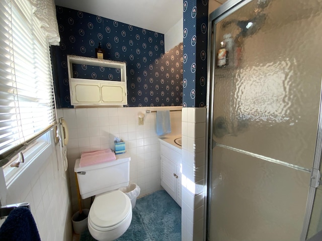 bathroom featuring vanity, toilet, a shower with door, and tile walls