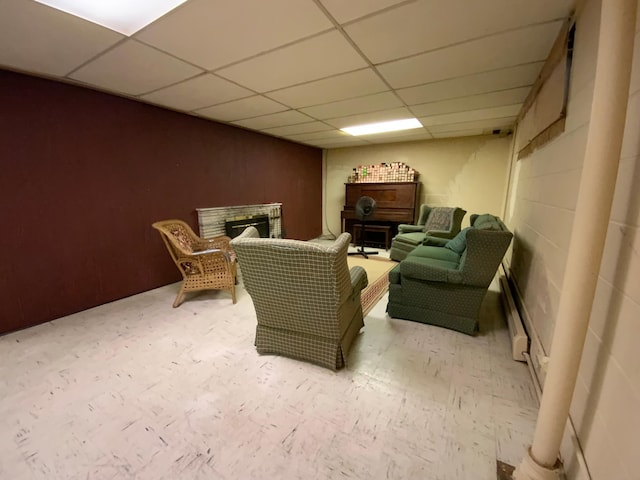 living area featuring a baseboard heating unit and a drop ceiling