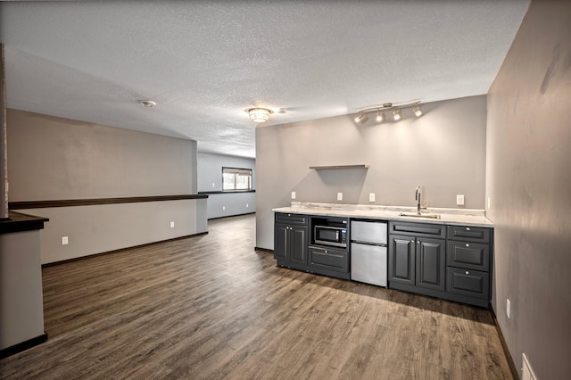 bar with stainless steel appliances, sink, a textured ceiling, and dark hardwood / wood-style floors