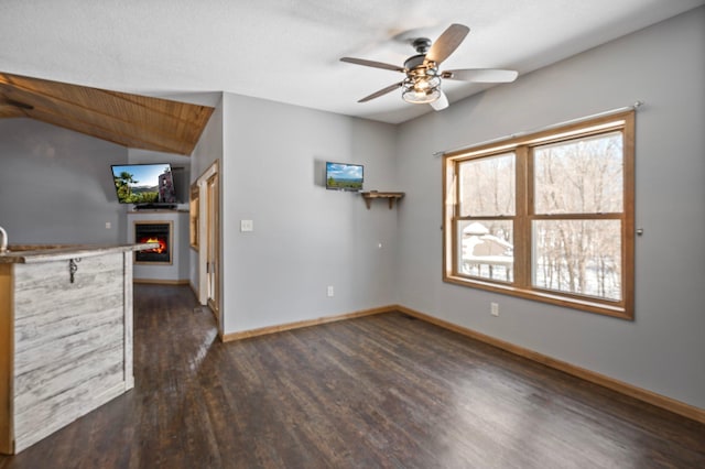 unfurnished living room with ceiling fan, dark hardwood / wood-style floors, and vaulted ceiling