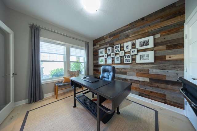 office space with light wood-type flooring, a textured ceiling, and wood walls