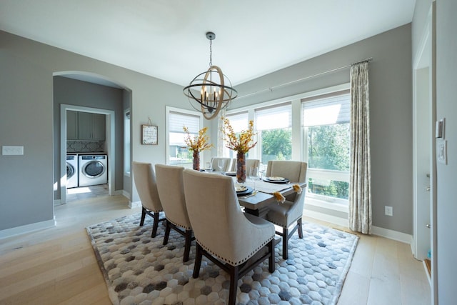 dining space with separate washer and dryer, an inviting chandelier, and light hardwood / wood-style floors