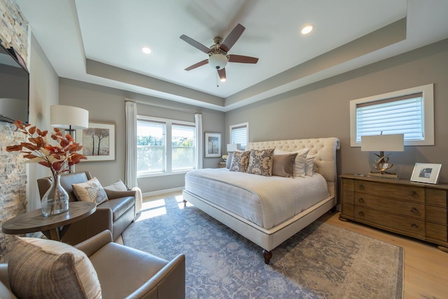 bedroom with hardwood / wood-style floors, a raised ceiling, and ceiling fan