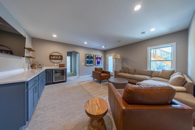 carpeted living room with wine cooler and indoor wet bar