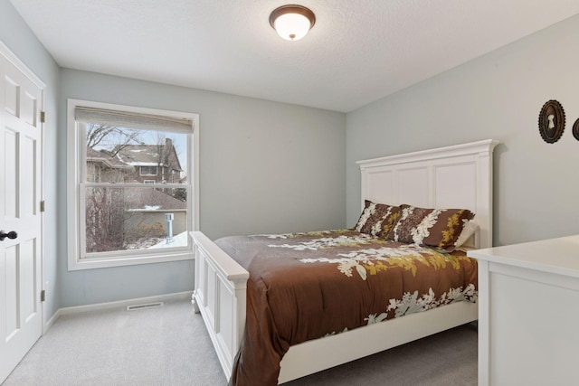 bedroom featuring a textured ceiling, baseboards, visible vents, and light carpet