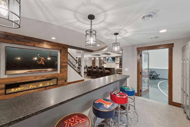 bar featuring a glass covered fireplace, a community bar, recessed lighting, decorative light fixtures, and baseboards