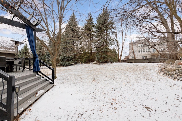 yard covered in snow with a wooden deck and outdoor dining space