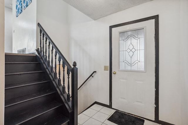 foyer entrance featuring a textured ceiling and light tile patterned floors