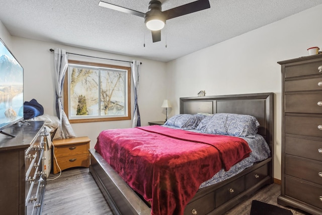 bedroom with ceiling fan, dark hardwood / wood-style floors, and a textured ceiling