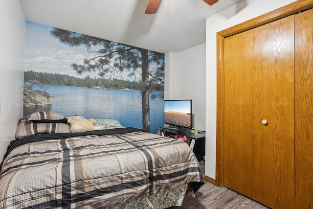 bedroom with ceiling fan, wood-type flooring, and a textured ceiling