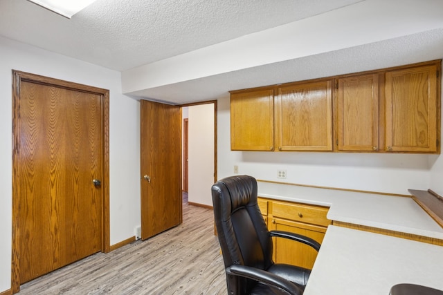 office area featuring built in desk, a textured ceiling, and light wood-type flooring