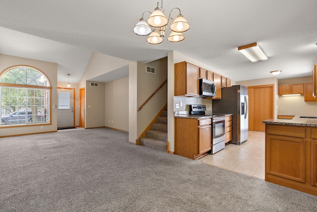 kitchen featuring stone counters, hanging light fixtures, stainless steel appliances, light carpet, and vaulted ceiling