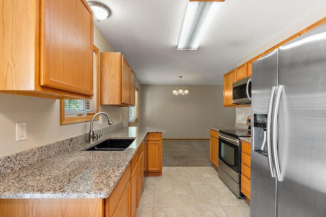 kitchen with stainless steel appliances, light stone countertops, sink, and hanging light fixtures