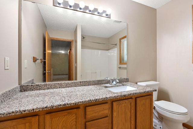 bathroom featuring walk in shower, vanity, and toilet