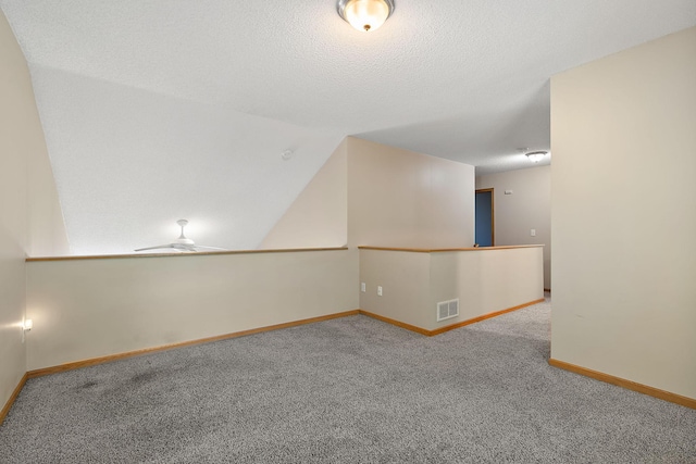 spare room featuring ceiling fan, a textured ceiling, and carpet