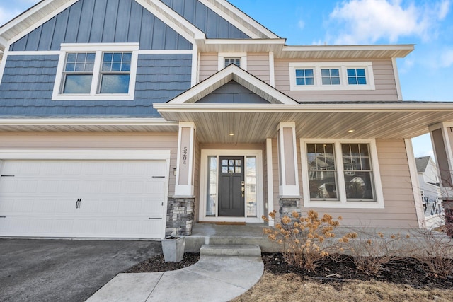 view of front of home featuring board and batten siding, covered porch, a garage, and aphalt driveway