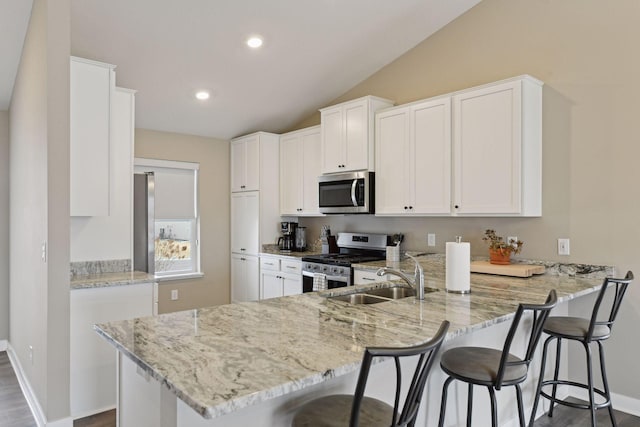 kitchen featuring sink, appliances with stainless steel finishes, kitchen peninsula, light stone countertops, and white cabinets