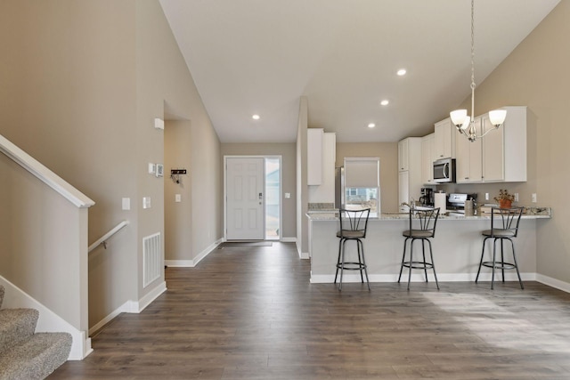 kitchen with pendant lighting, white cabinetry, a kitchen breakfast bar, stainless steel appliances, and kitchen peninsula