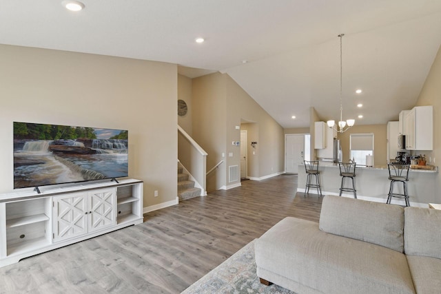 living room featuring high vaulted ceiling, a chandelier, and light hardwood / wood-style flooring