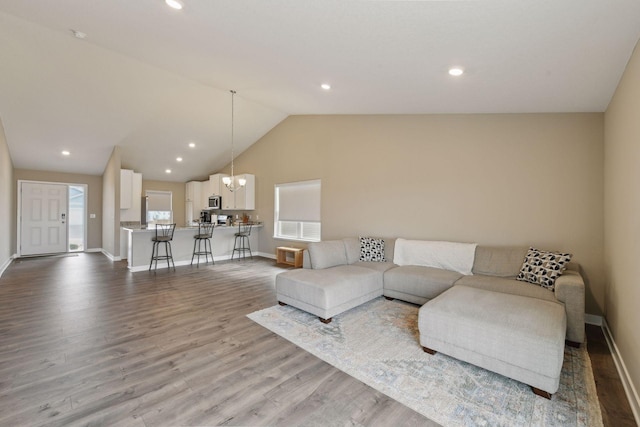 living room with lofted ceiling, light hardwood / wood-style floors, and a chandelier