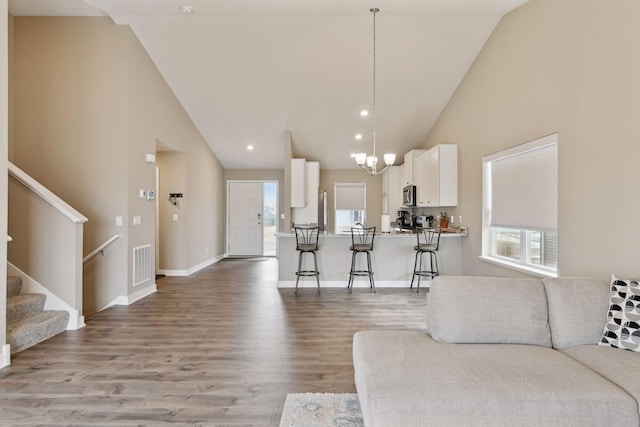 living room with light hardwood / wood-style flooring, high vaulted ceiling, and plenty of natural light