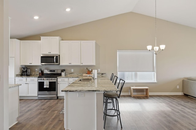 kitchen featuring white cabinetry, light stone counters, hanging light fixtures, a kitchen breakfast bar, and stainless steel appliances