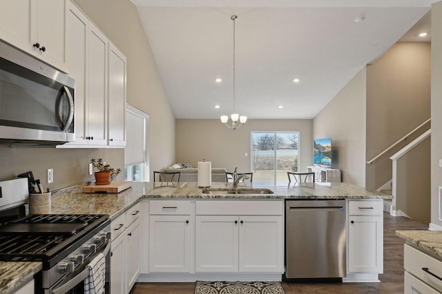 kitchen with sink, white cabinetry, light stone counters, appliances with stainless steel finishes, and pendant lighting