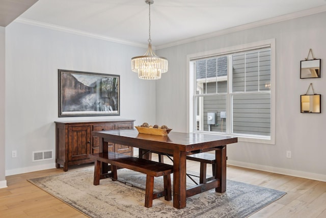 dining space featuring a notable chandelier, baseboards, light wood-style floors, and crown molding